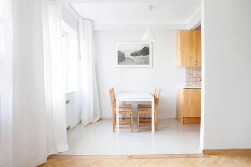 a white kitchen with a table and chairs at Elegancki apartament / wi fi / centrum in Warsaw