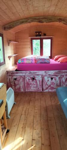 a bedroom with a bed in a wooden cabin at Jolie Roulotte in Issendolus