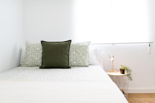 a white bed with a green pillow on it at Centro y Confort: Junto a Corte Inglés in Granada