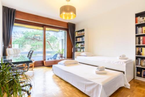 Habitación con 2 camas, mesa y ventana en Tourelle 2 - Spacieux appartement dans le centre de Genève, en Ginebra