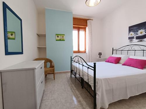 a bedroom with a bed with pink pillows and a desk at Casa Laura 100m dalla sabbia in Lido Marini