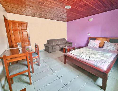 um quarto com uma cama, uma mesa e um sofá em ORION RESIDENCY BONABERIE em Douala