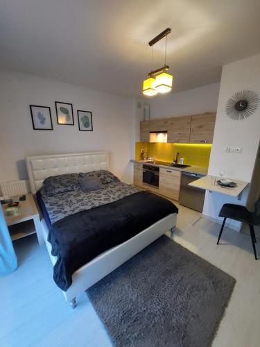 a bedroom with a bed and a desk and a kitchen at Apartament Olif in Rzeszów