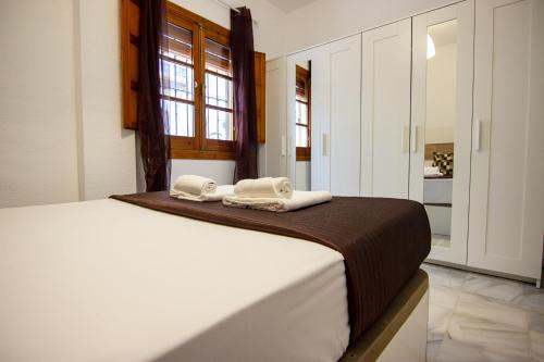 een slaapkamer met een bed met twee handdoeken erop bij RentalSevilla A los pies de la Alameda de Hércules in Sevilla