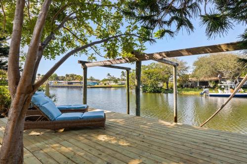 a wooden deck with a chair on the water at Coconut Cove - Heated Pool And Canal in Cocoa Beach