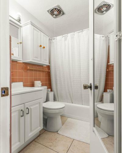 a white bathroom with a toilet and a sink at Coconut Cove - Heated Pool And Canal in Cocoa Beach