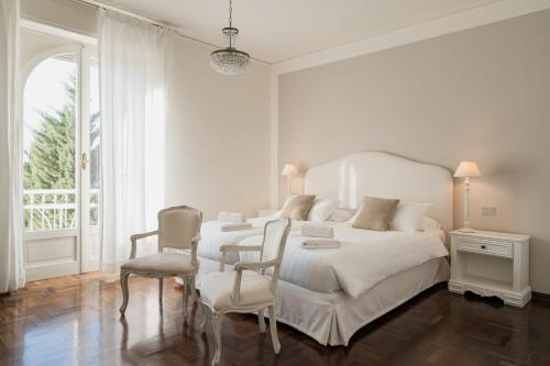 a white bedroom with two beds and two chairs at Villa Telli in Garda