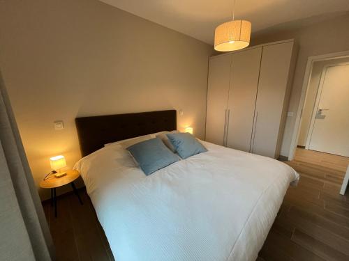 a bedroom with a large bed with two blue pillows at Logies La Parmentière in De Panne