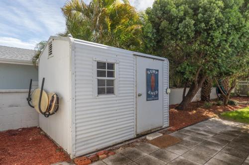 a small white shed in front of a house at Surfs Up - Retreat At The Beach With Heated Pool in Melbourne Beach