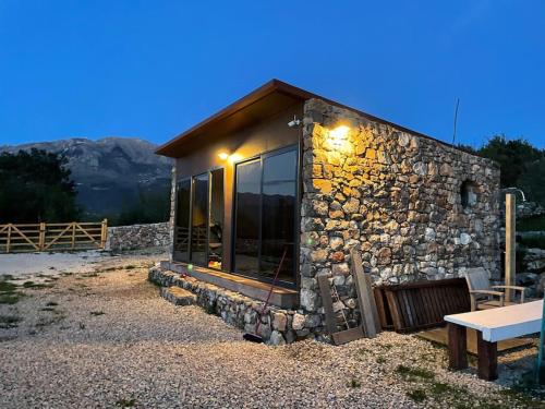 a stone house with a bench in front of it at Glamping nature Tiny house in Kotor
