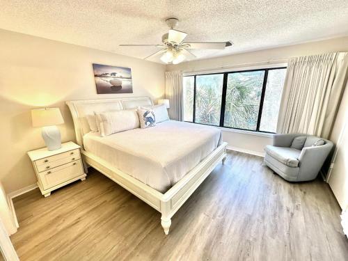 Un dormitorio con una cama y una silla y una ventana. en 5177 Beachwalk, en Destin