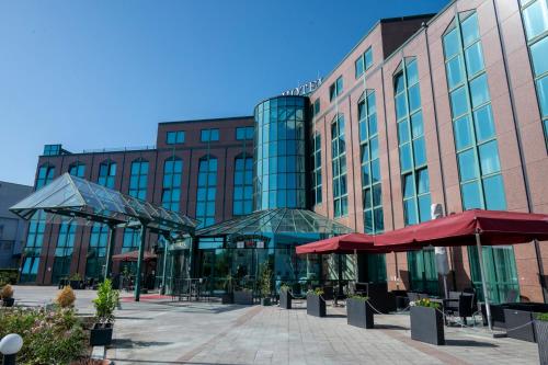 a building with tables and umbrellas in front of it at Hotel Amadeus Frankfurt in Frankfurt/Main
