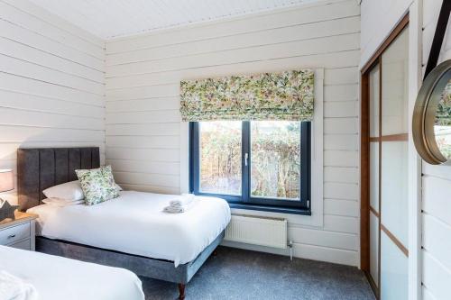 羅伊登的住宿－Roydon Marina - Lodge 3 - Hot Tub，一间卧室设有两张床和窗户。