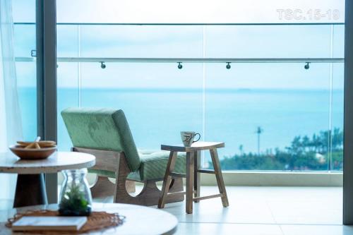 une chambre avec une chaise, une table et une fenêtre dans l'établissement The Sóng Apartment Sea View - Căn Hộ Biển Nghỉ Dưỡng - Hao's Homestay, à Vung Tau