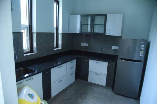 a kitchen with white cabinets and a black refrigerator at Raj Farms near Kukus by Raj Kothi in Jaipur