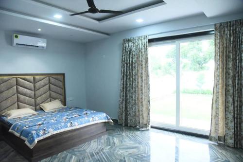 a bedroom with a bed and a large window at Raj Farms near Kukus by Raj Kothi in Jaipur