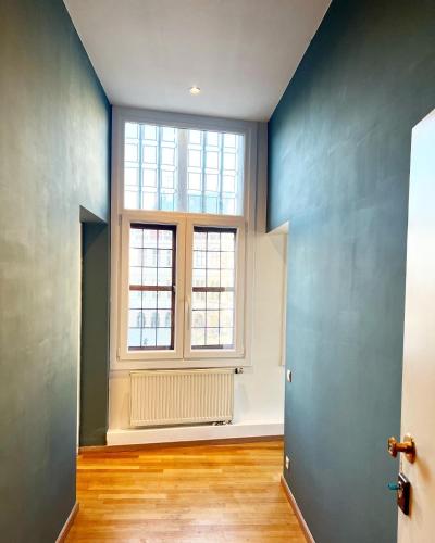 an empty room with a large window and wooden floors at Le FauBourg Suites in Antwerp
