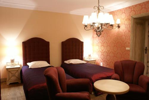 a bedroom with two beds and a table and a chair at Berberys Park Hotel in Kazimierz Dolny