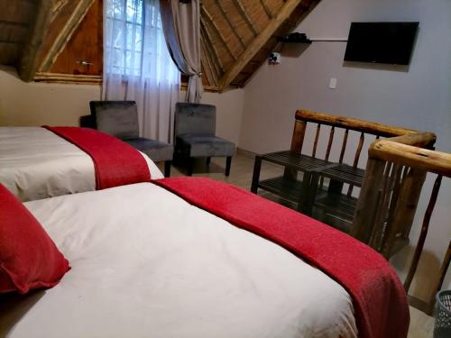 a bedroom with two beds and a television in a room at Shingalana Guest Lodge in Hazyview