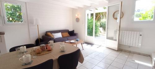 ein Wohnzimmer mit einem Tisch und einem Sofa in der Unterkunft Semaphore2- Maison au calme - Piscine - La Chaume in Les Sables-dʼOlonne