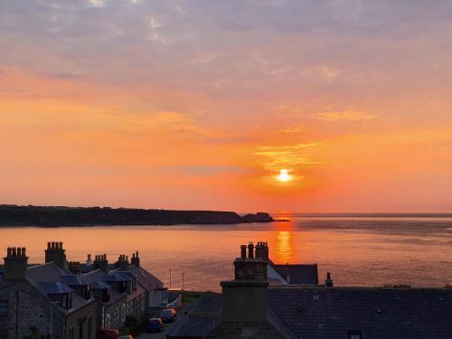 a sunset over a body of water with houses at Salt View in Cullen