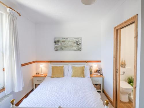 a white bedroom with a bed and a toilet at Lantern Cottage in Colyton