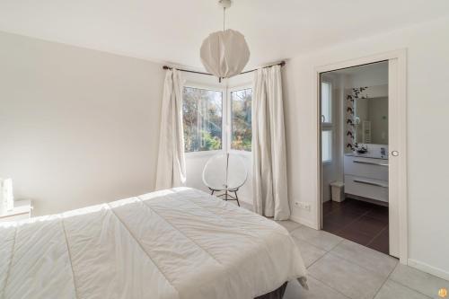 een witte slaapkamer met een bed en een raam bij Villa 4 étoiles à 50M la plage tranquille et lumineuse à TREGASTEL Réf -135 in Trégastel