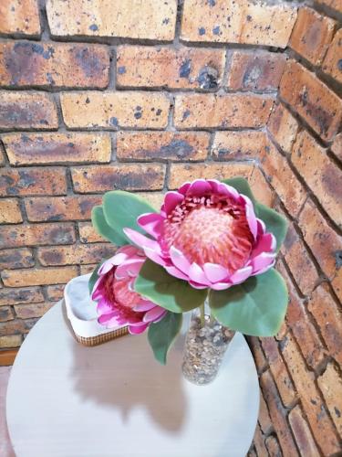 a vase with a pink flower on a table at Shingalana Guest Lodge in Hazyview
