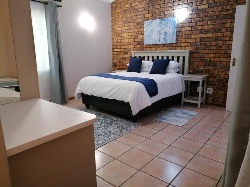 a bedroom with a bed and a brick wall at Shingalana Guest Lodge in Hazyview
