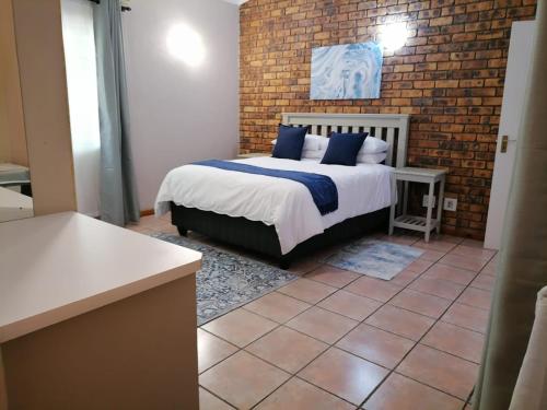 a bedroom with a bed and a brick wall at Shingalana Guest Lodge in Hazyview