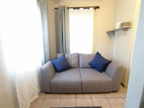 a couch with two blue pillows in a living room at Shingalana Guest Lodge in Hazyview