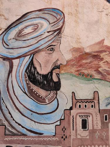 a painting of a man with a hat and a city at Le Retour au calme Maison d'hôtes in Tinerhir