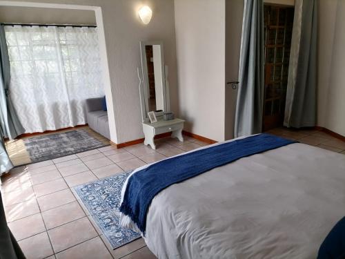 a bedroom with a bed and a room with a couch at Shingalana Guest Lodge in Hazyview
