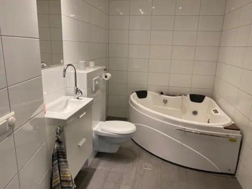 a bathroom with a toilet and a tub and a sink at Húsavík 2 Bedroom Apartment in Húsavík