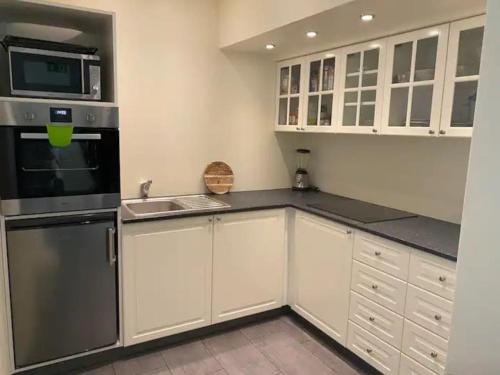 uma cozinha com armários brancos e electrodomésticos de aço inoxidável em Húsavík 2 Bedroom Apartment em Húsavík