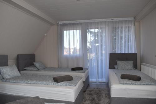 two beds in a room with a window at Partyház Gödöllő in Gödöllő