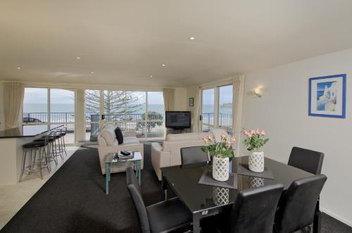 a living room with a couch and a table with chairs at Pavilion Beachfront Apartments in Mount Maunganui