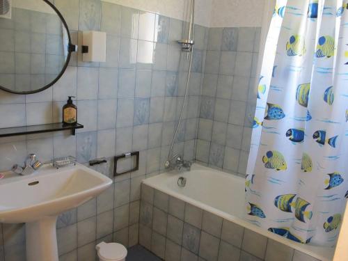 łazienka z umywalką, wanną i zasłoną prysznicową w obiekcie Maison avec jardin, WIFI, à 50m de la plage à TREGASTEL - Réf 195 w mieście Trégastel