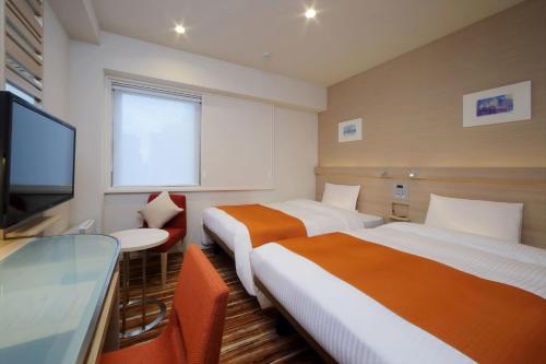 a hotel room with two beds and a flat screen tv at Keio Presso Inn Akasaka in Tokyo