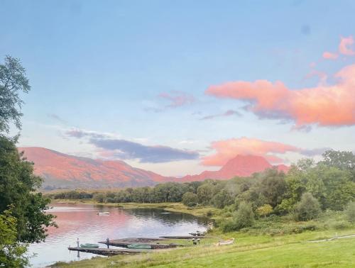 a river with boats on it with mountains in the background at Loch Maree Hotel in Talladale