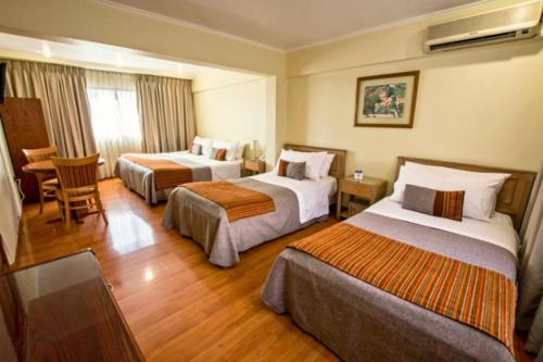 um quarto de hotel com duas camas e uma mesa em HOTEL DACARLO em Santiago