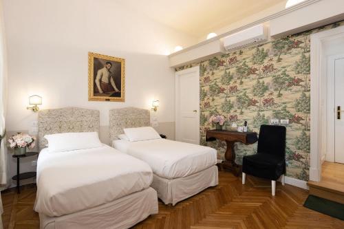 a bedroom with two beds and a painting on the wall at Relais Donna Lucrezia in Rome