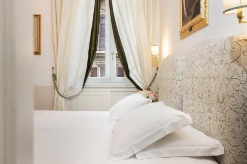 a bedroom with a bed with white pillows and a window at Relais Donna Lucrezia in Rome
