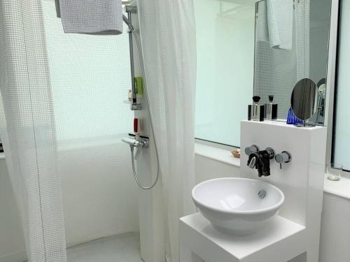 une salle de bain blanche avec un lavabo et une douche dans l'établissement Villa avec jardin à 370m de la plage de Landrellec à PLEUMEUR-BODOU REF-245, à Pleumeur-Bodou