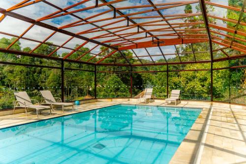 an outdoor pool with a pergola and a swimming pool at Hotel Vila Inglesa in Campos do Jordão