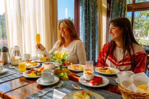 two women sitting at a table eating breakfast at Hotel Vila Inglesa in Campos do Jordão