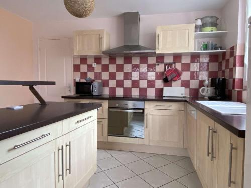 une cuisine avec des armoires blanches et un comptoir noir dans l'établissement Maison agréable 6 pers à l'Ile Grande, proche plages en PLEUMEUR-BODOU REF-268, à Pleumeur-Bodou