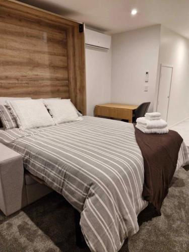 a bedroom with a large bed with a wooden headboard at Cosy CBD Studio Apartment 6 in Christchurch