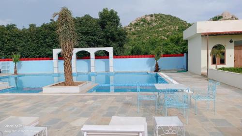 a pool with tables and chairs next to a building at Braj samode resort in Sāmod