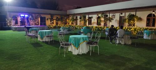 a group of tables and chairs in a room with lights at Braj samode resort in Sāmod